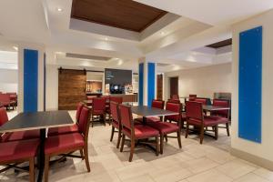 杜兰特杜兰特快捷假日&套房酒店的用餐室配有桌子和红色椅子
