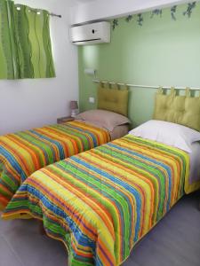 TolloAlba Marina Rooms的客房内的两张床和色彩缤纷的毯子