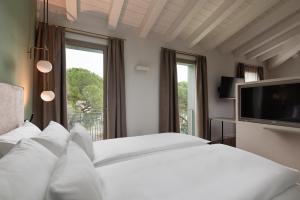 格拉迪斯卡迪松佐HT Hotel Trieste的卧室配有白色的床和电视。