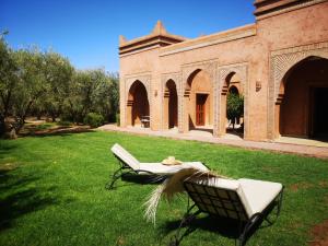马拉喀什Domaine Casa Cecilia的坐在建筑物旁边的草上的一个椅子