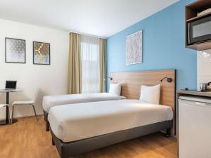 塞纳河畔伊夫里巴黎奎爱艺瑞爱达格公寓式酒店的酒店客房配有两张床和一张书桌