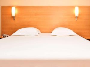 圣艾米隆波尔多圣爱美浓宜必思酒店的一张带两个枕头的大白色床