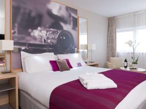 巴黎巴黎爱乐厅拉维莱特19号美居酒店的一间卧室配有一张大床,提供紫色和白色枕头