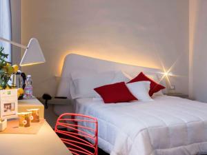 巴勒莫Ibis Styles Palermo President的卧室配有带红色枕头的白色床
