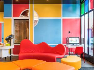库尔布瓦库尔布瓦巴黎拉德芳斯宜必思尚品酒店的客厅设有红色的沙发和色彩缤纷的墙壁