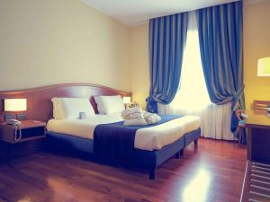 热那亚热那亚圣比亚焦美居酒店的一间卧室配有一张蓝色窗帘的大床