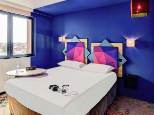 阿尔比ibis styles Albi Centre Le Theatro的卧室配有白色大床和蓝色的墙壁