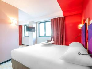 阿尔比ibis styles Albi Centre Le Theatro的卧室配有一张白色大床和红色墙壁