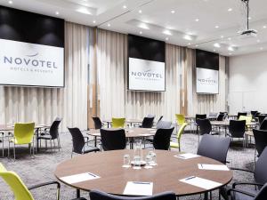 霍夫多普诺富特阿姆斯特丹史基浦机场酒店的一间会议室,配有桌椅和屏幕