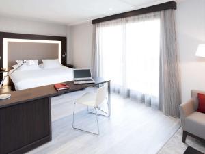 马德里马德里市中心诺富特酒店的一间卧室配有一张床和一张带笔记本电脑的书桌