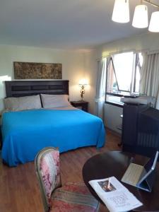 圣地亚哥科斯塔内拉中心公寓酒店的一间卧室配有蓝色的床、一张桌子和一把椅子