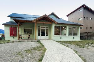 厄尔查尔坦Hostería Vertical Lodge的前面设有野餐长椅的绿色房子