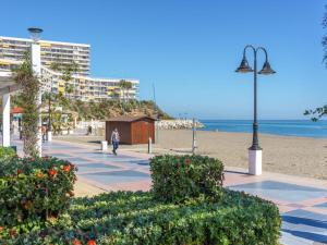 多列毛利诺斯Apartamentos LOLA y MANUELA en primera línea playa Carihuela con excelente Terraza-jardin de 80 m2 frente al Mar con aparcamiento privado Ideal para descansar oyendo las olas del Mar的轻极在海滩上行走的人