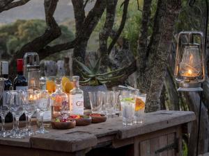 阿马卡拉保护区HillsNek Safari Camp – Amakhala Game Reserve的桌子上放着眼镜和瓶装葡萄酒