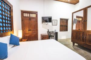 贾夫纳Thambu Illam的卧室配有一张白色大床和电视。