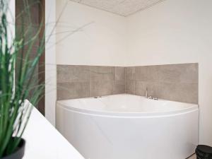 灵克宾6 person holiday home in Ringk bing的浴室设有白色浴缸,浴室设有瓷砖墙