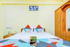哥印拜陀FabExpress Ragu Residency的一间卧室配有一张带五颜六色棉被的床