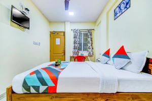 哥印拜陀FabExpress Ragu Residency的卧室配有一张带彩色枕头的大型白色床。