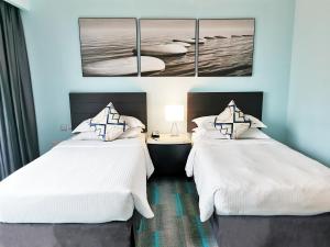 新山提斯特尔的酒店客房,配有两张带白色床单的床
