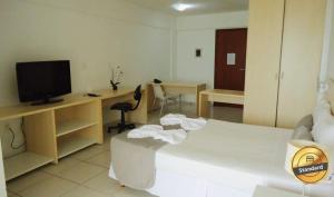 纳塔尔Terrazzo Ponta Negra Flat JD的客房设有床、电视和书桌。
