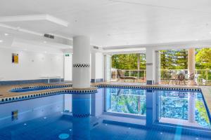 黄金海岸奥斯卡主海滩度假酒店的一个带蓝色瓷砖地板和柱子的游泳池