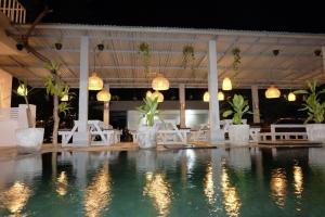 克罗柏坎Pom Pom's Bali Apartments的游泳池配有白色的桌椅和灯光