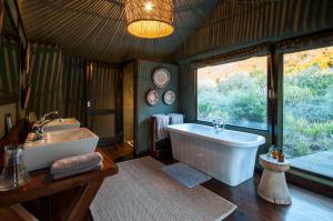 阿马卡拉保护区HillsNek Safari Camp – Amakhala Game Reserve的带浴缸、水槽和窗户的浴室
