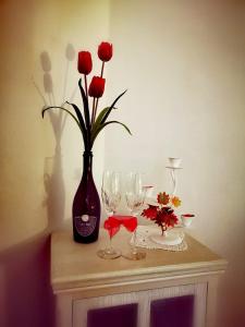 贝内文托Anamonì Bed and Relax的一张带红玫瑰花瓶和酒杯的桌子