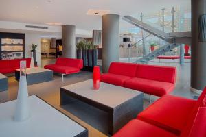 帕多瓦NH帕多瓦酒店的客厅配有红色的沙发和桌子