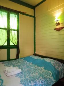 曼谷Baan Tepa Boutique House的窗户和毛巾的客房内的一张床位