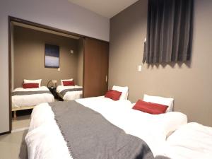 札幌UCHI Living Stay Sapporo Kikusui的酒店客房 - 带两张带红色枕头的床
