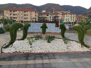 费特希耶Fethiye City Aparts的一座公园内植物的雕塑,建筑背景