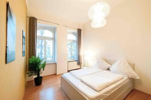 莱比锡Altbauwohnung direkt an der Karli mit Balkon - Netflix inklusive的卧室配有白色的床铺和盆栽植物