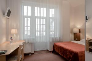 里加Hotel Edvards的一间卧室配有一张床、一张书桌和一个窗户。
