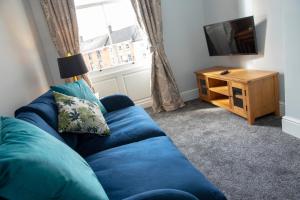 阿什伯恩Dovedale的客厅里设有蓝色的沙发,配有电视