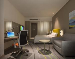 成都成都金牛智选假日酒店的酒店客房配有一张床、一张书桌和一台笔记本电脑
