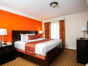 西奥兰治威尔希尔格兰德酒店的一间卧室配有一张带橙色墙壁的大床