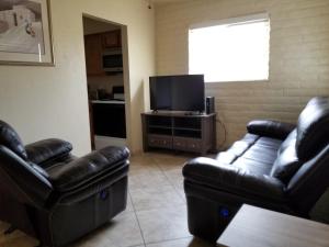 土桑Tucson Airport Oasis的客厅配有两张真皮沙发和一台平面电视