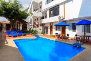 阿约拉港朱迪之家酒店的一座带蓝色椅子和遮阳伞的游泳池位于一座建筑旁边