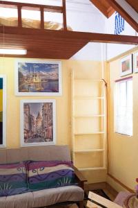提华纳Greek Cottage Playas de Tijuana的一间设有床铺的客房,墙上挂有图片