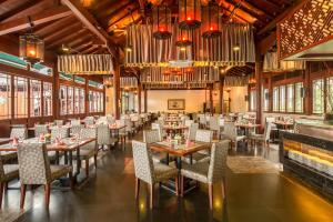 三亚三亚亚龙湾华宇度假酒店的用餐室配有桌椅和吊灯。