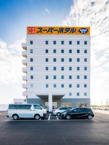 神栖市Super Hotel Kashima的停车场内有车辆的旅馆