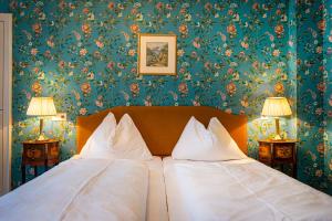 巴德加斯坦怡东别墅休闲酒店的卧室配有白色枕头和花卉壁纸