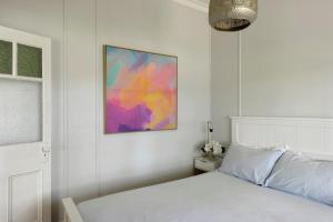 苏塞克斯入口Calm Waters Waterfront Cottages的卧室配有白色的床和墙上的绘画作品