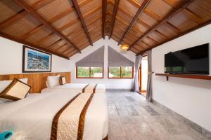 An Bàn (2)Lama Beach Villa的一间卧室配有两张床和一台平面电视