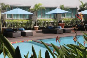 万隆ASTON Tropicana Hotel Bandung的一座游泳池旁,设有沙发和遮阳伞