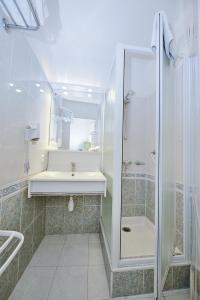 巴拉吕克莱班Azur Hotel的带淋浴、盥洗盆和镜子的浴室