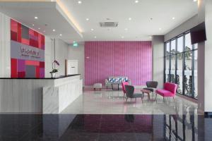 当格浪favehotel Hasyim Ashari Tangerang的大堂设有椅子和粉红色的墙壁