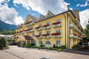 迪马罗Alpholiday Dolomiti Wellness & Family Hotel的大型黄色建筑,设有窗户和阳台