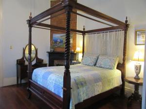新奥尔良Garden District Bed and Breakfast的一间卧室设有一张天蓬床和两张桌子